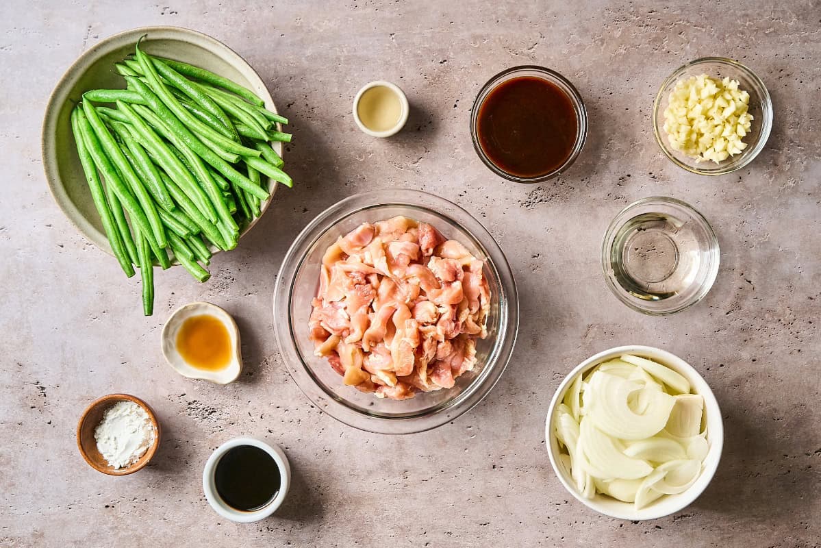 overhead view of portioned ingredients for chicken and green bean stir fry with hoisin sauce in individual containers.