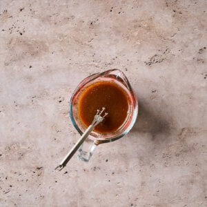 hoisin stir fry sauce in a glass liquid measuring cup with a mini whisk.