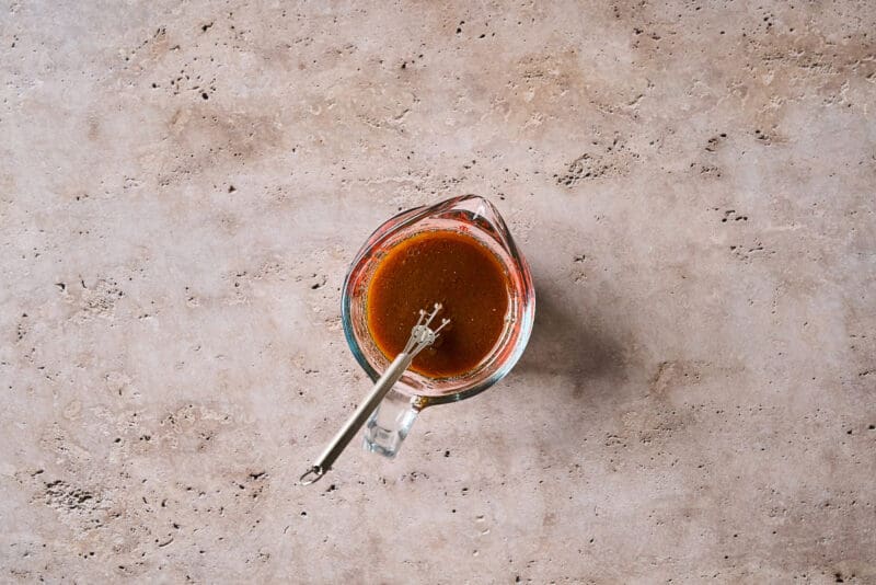 hoisin stir fry sauce in a glass liquid measuring cup with a mini whisk.