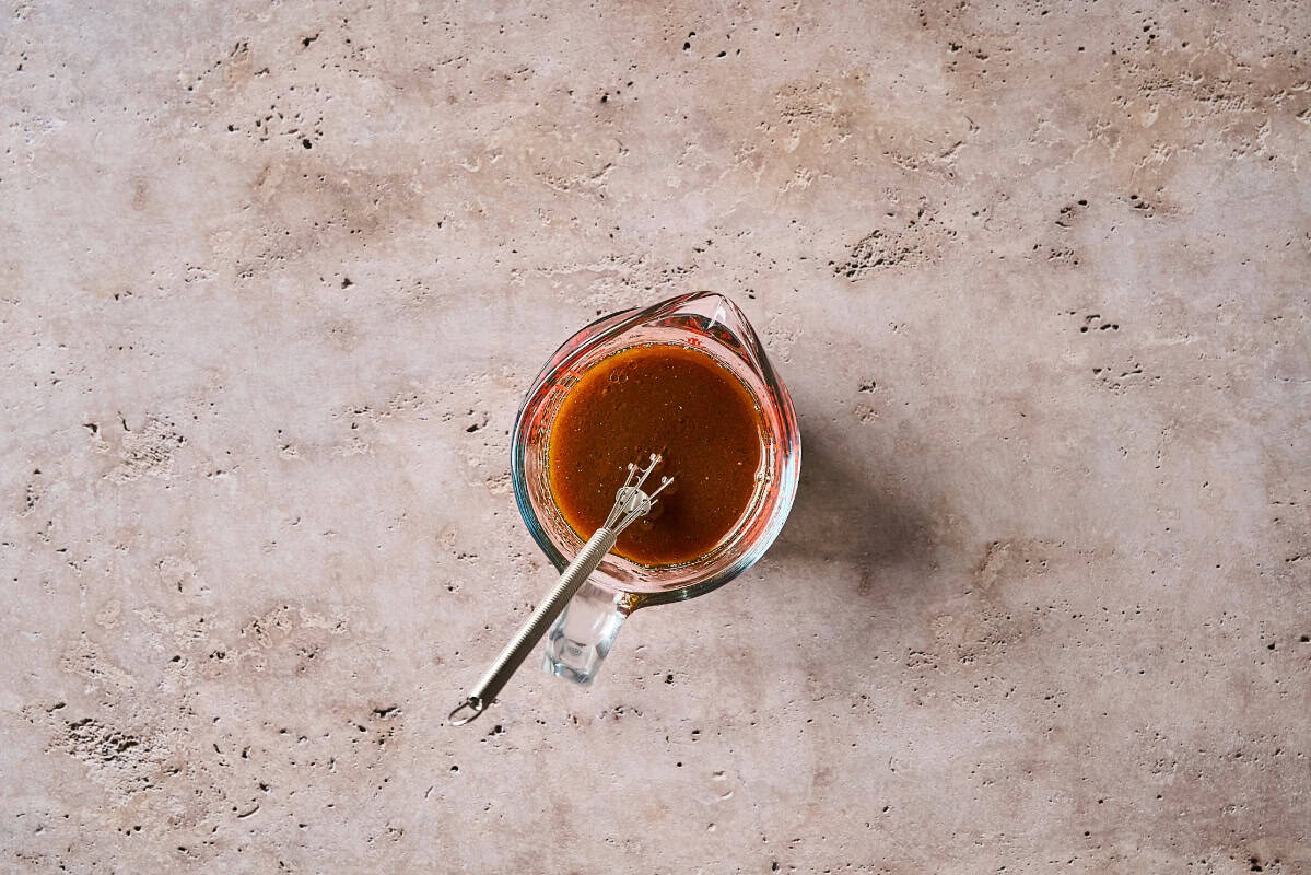 hoisin stir fry sauce in a glass liquid measuring cup with a mini whisk.