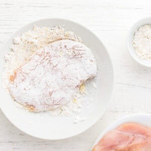 dredging chicken breasts in seasoned flour.