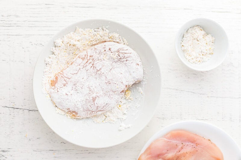 dredging chicken breasts in seasoned flour.