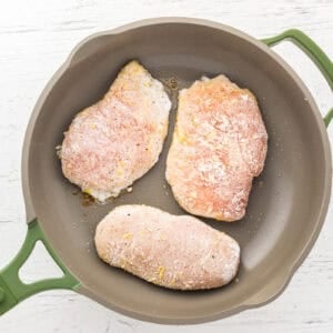 floured chicken breasts searing in a pan.