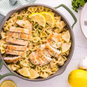 overhead view of lemon chicken pasta in a pan with lemon wedges and parsley.