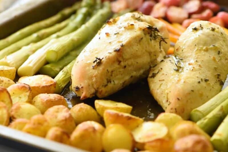 Chicken breast, potatoes, and veggies on a sheet pan.