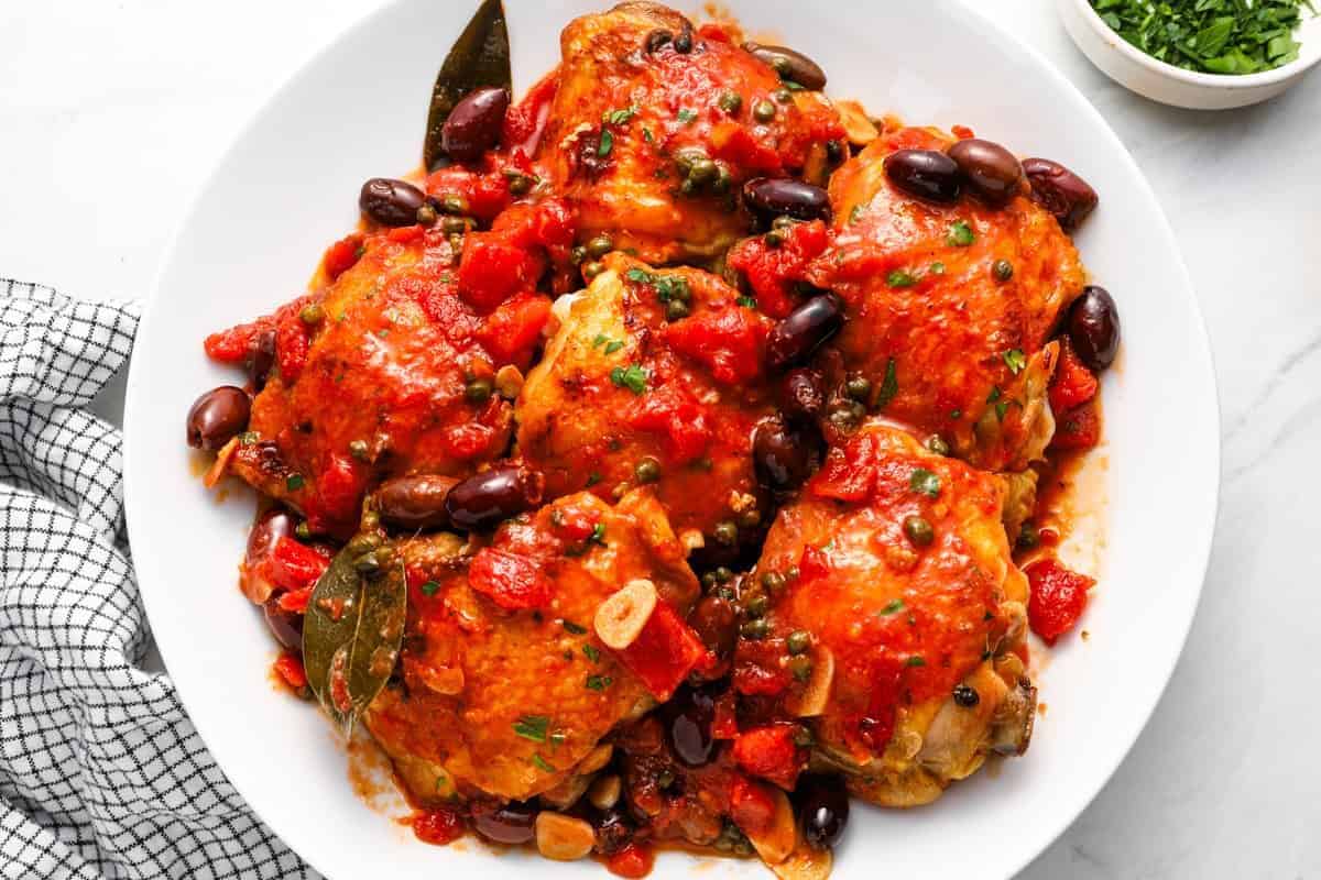 chicken puttanesca on a large white plate.