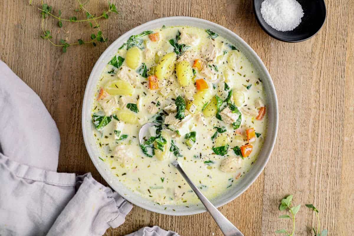 a bowl of olive garden chicken gnocchi soup with a spoon.