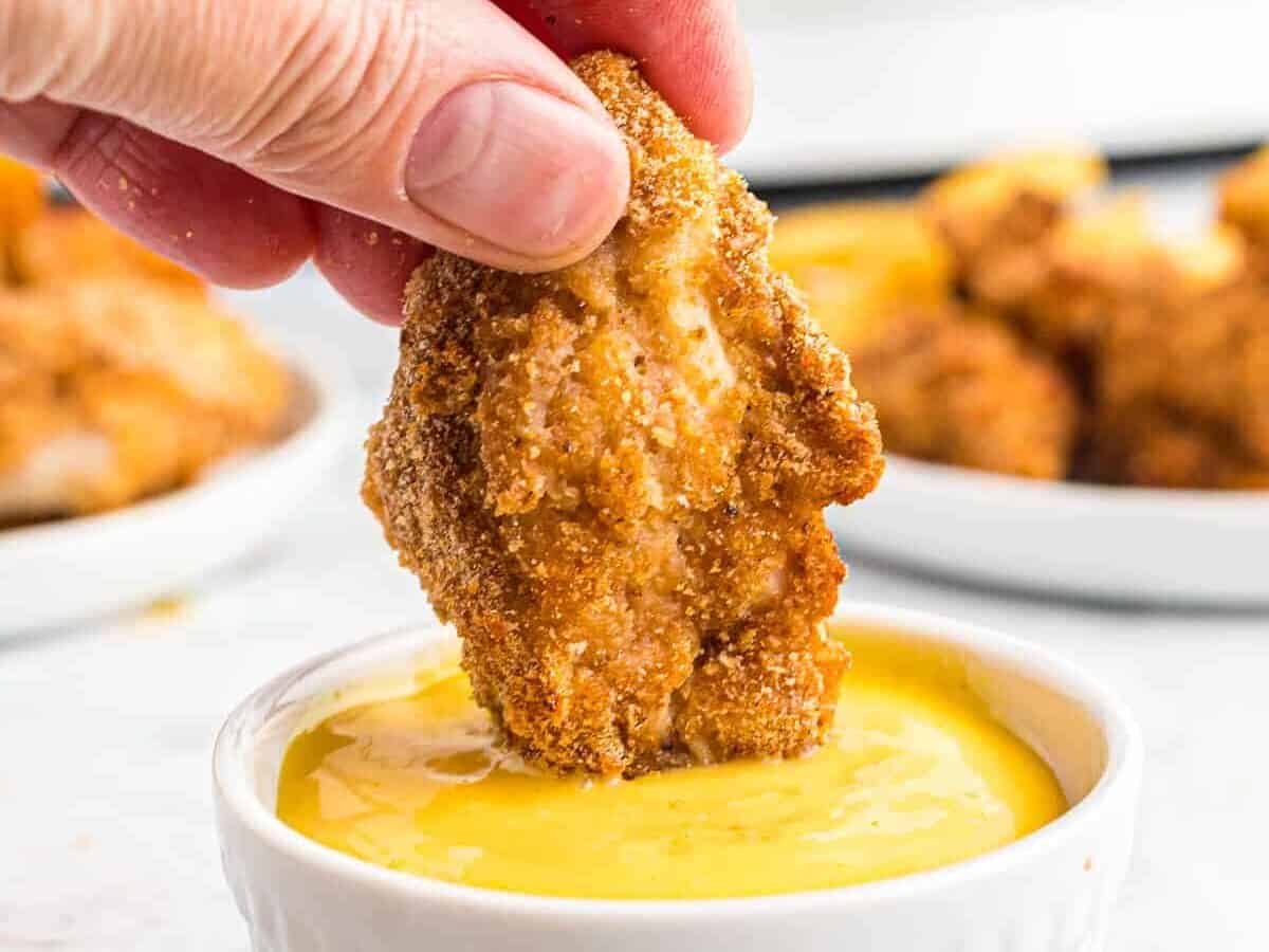 Dipping breaded chicken nugget in honey mustard.