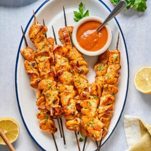 apricot chicken skewers on an oval serving tray with apricot dipping sauce.