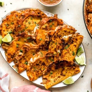 chicken birria tacos on an oval serving tray.