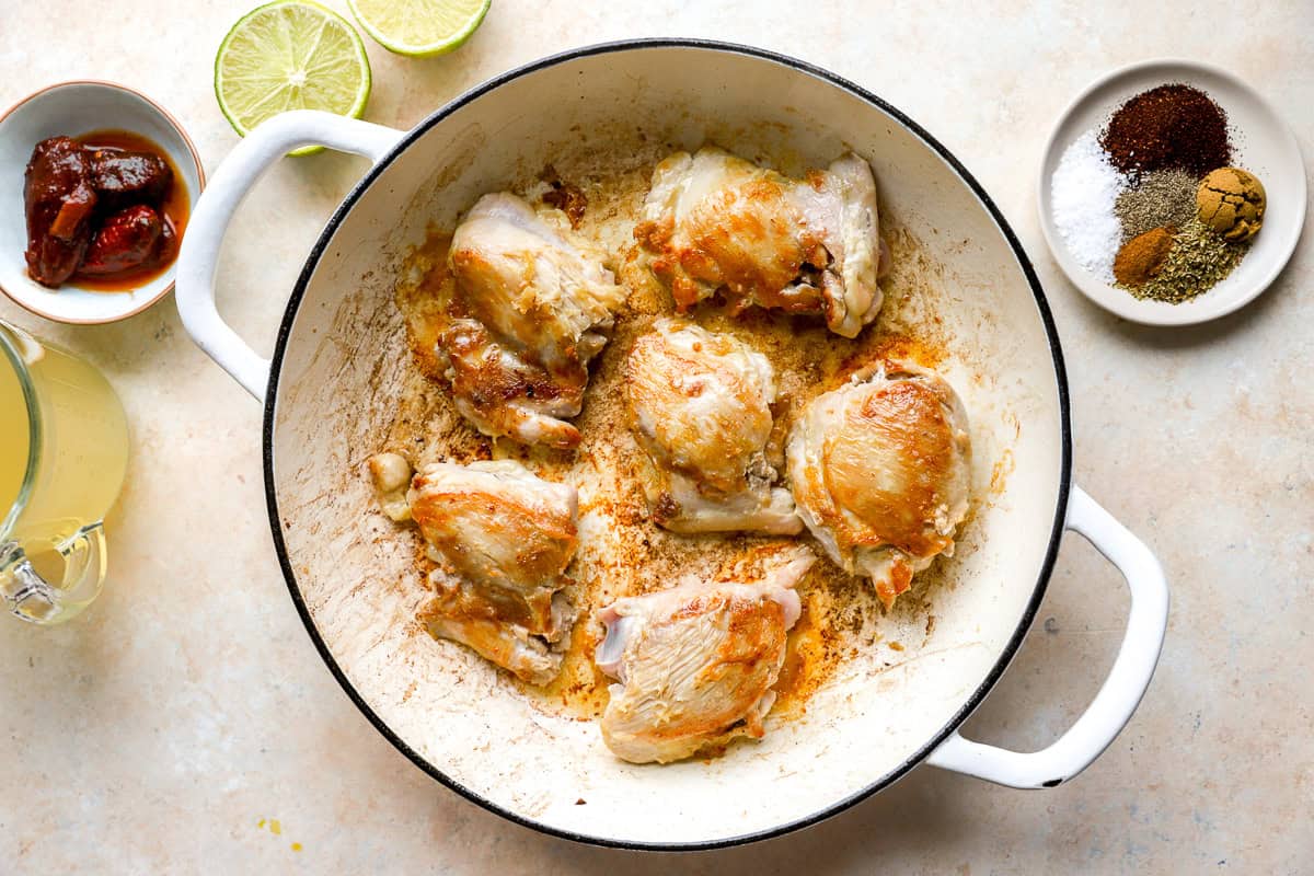 searing chicken thighs in a pan.