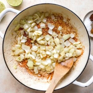 sautéeing onions in a pan with a wooden spoon.