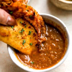 dipping a chicken birria taco into birria consommé.