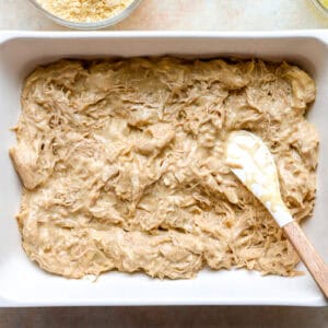 shredded chicken casserole mixture in a casserole dish with a rubber spatula.