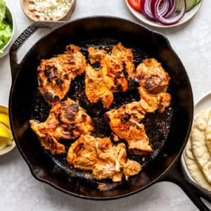 seared marinated chicken thighs in a cast iron pan.