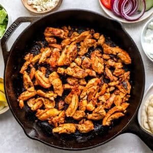 searing sliced chicken gyro meat in a cast iron skillet.