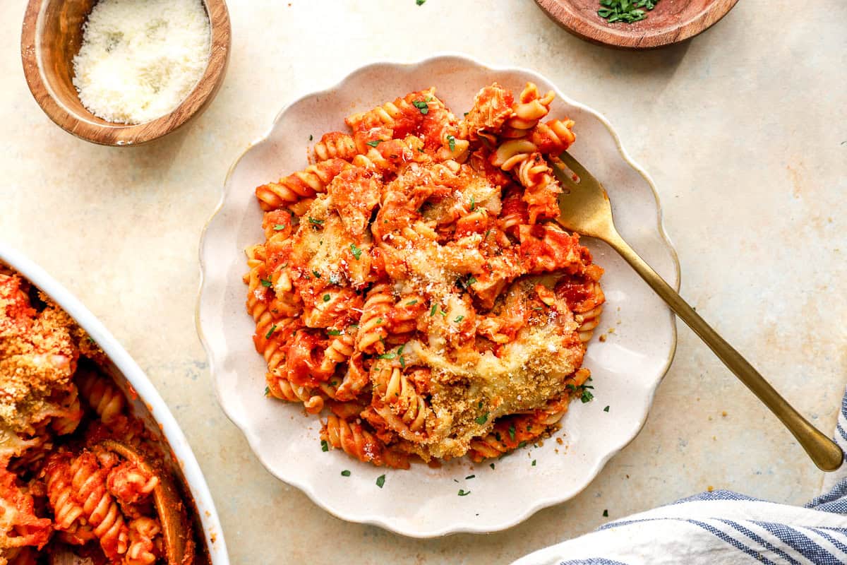 a serving of baked chicken parmesan pasta casserole on a white plate with a fork.