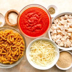 ingredients for chicken Parmesan casserole in individual bowls.