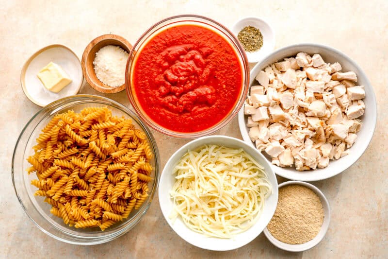 ingredients for chicken Parmesan casserole in individual bowls.