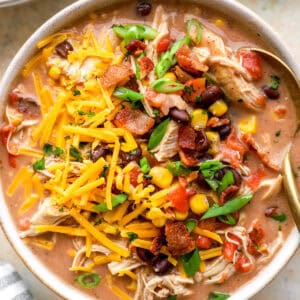 closeup of a bowl of crack chicken chili topped with bacon, cheese, and scallions.