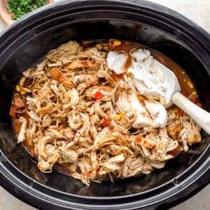 stirring cream cheese and shredded chicken into chili in a crockpot.