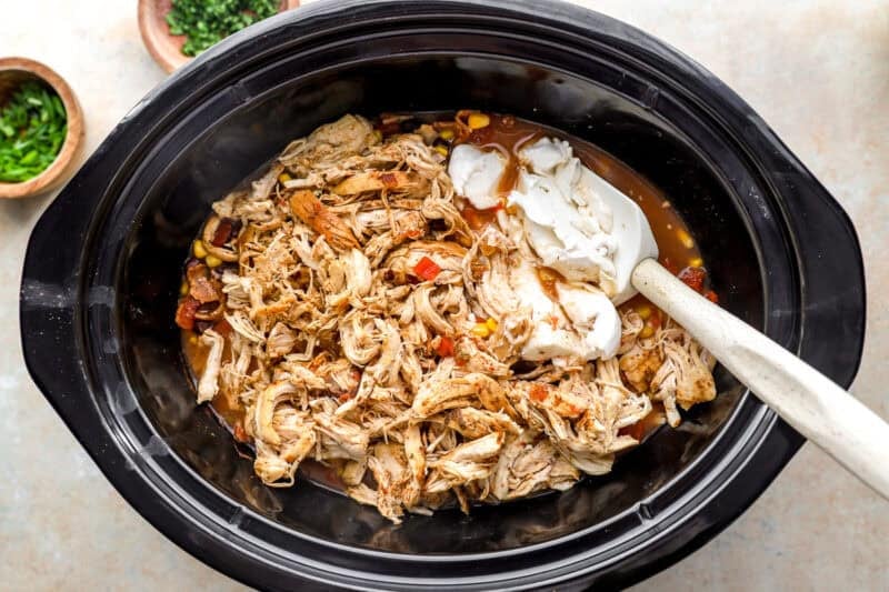 stirring cream cheese and shredded chicken into chili in a crockpot.