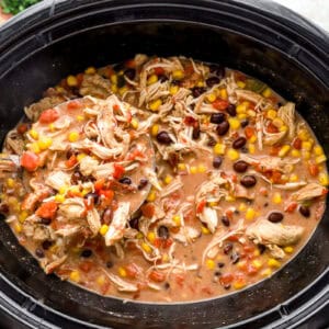 crack chicken chili in a crockpot with a ladle.