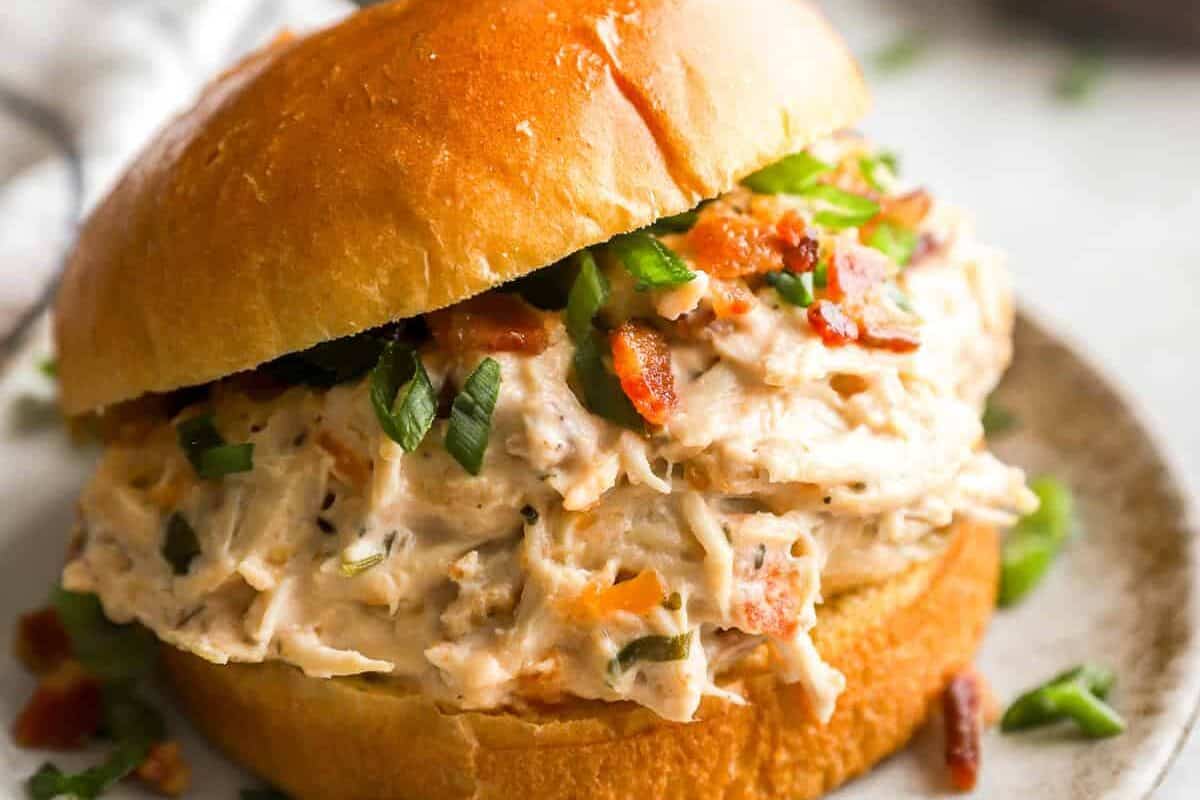 a serving of crockpot crack chicken on a hamburger bun.