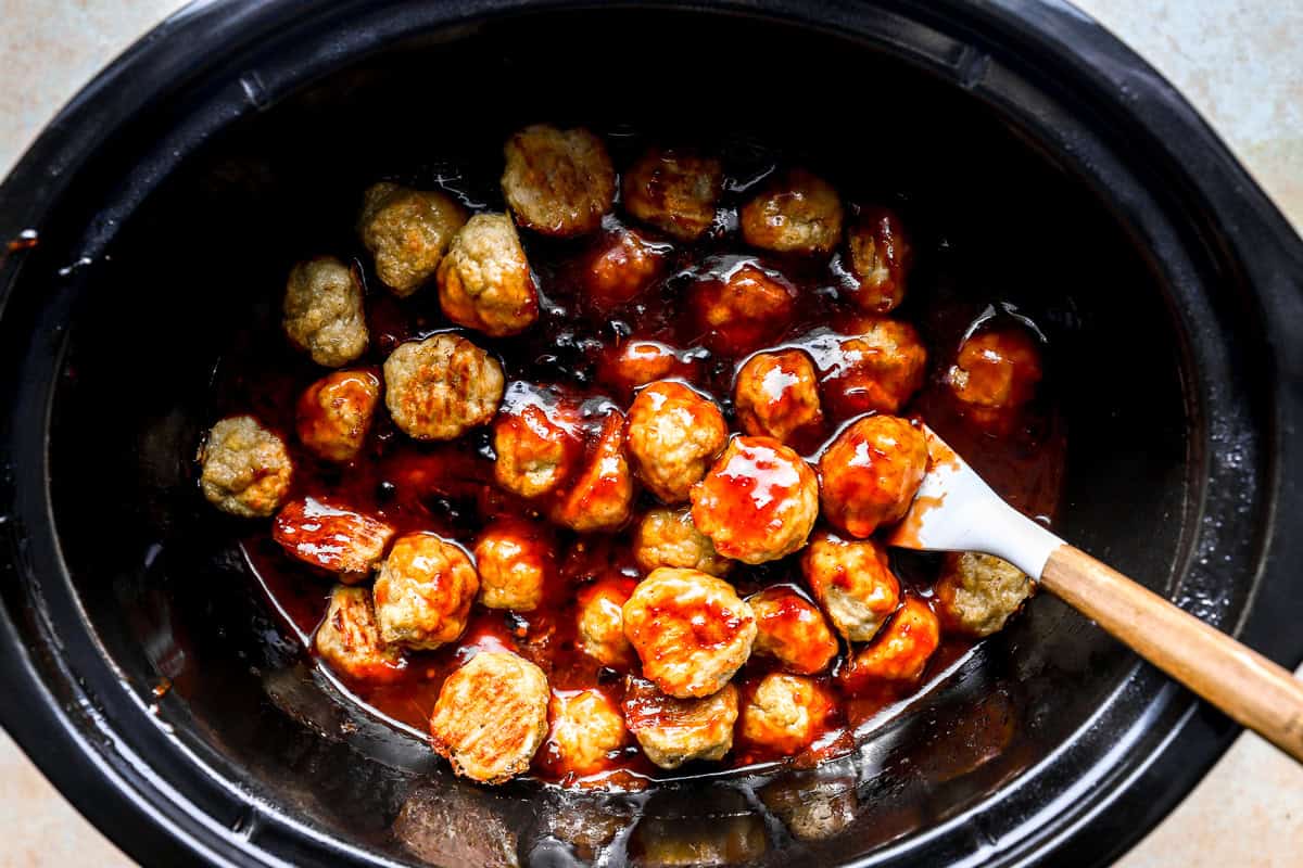 tossing chicken meatballs in grape jelly and chili sauce in a slow cooker with a rubber spatula.