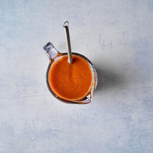 apricot marinade in a glass liquid measuring cup with a whisk.