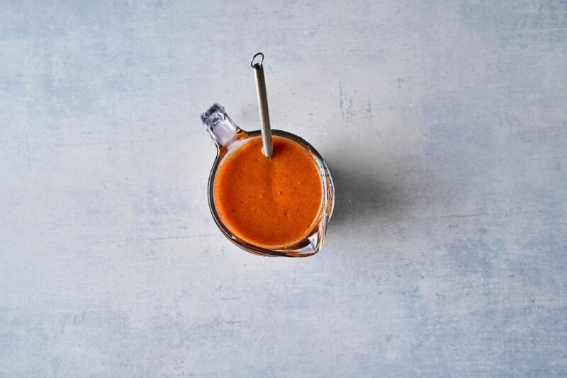 apricot marinade in a glass liquid measuring cup with a whisk.