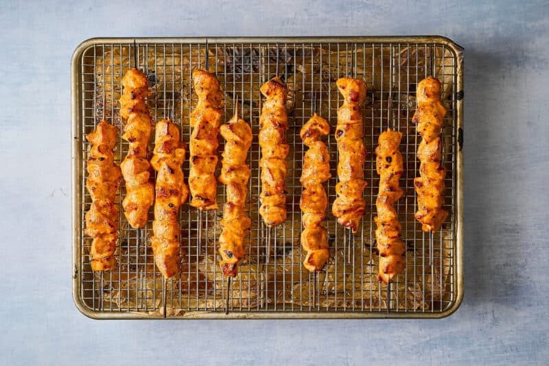 broiled apricot chicken skewers on a wire rack set in a baking sheet.