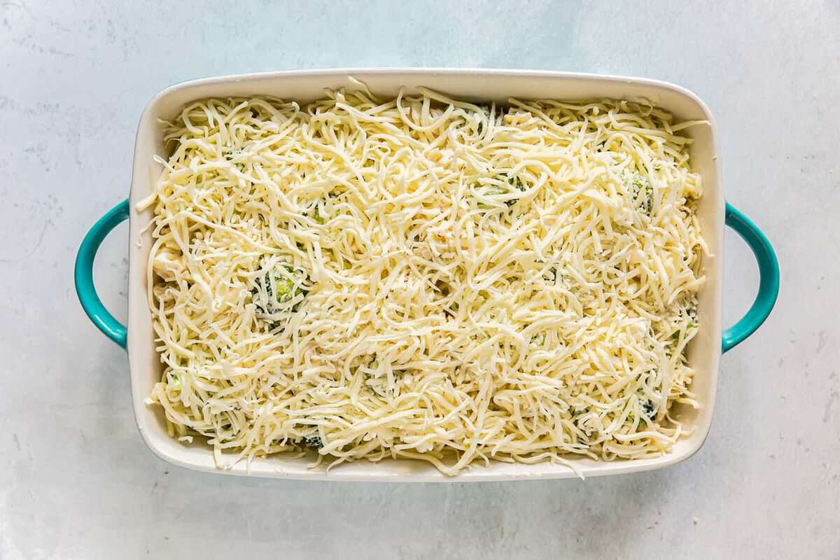 Chicken, broccoli, alfredo mixture layered into a baking dish, topped with shredded cheese.