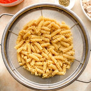 cooked rotini draining in a colander.