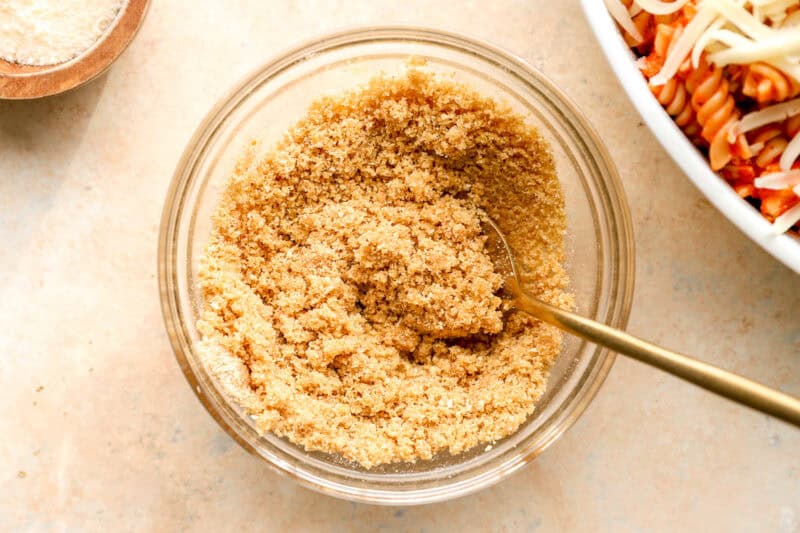 stirred breadcrumbs and melted butter in a small glass dish with a spoon.