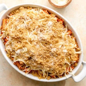 assembled chicken parmesan casserole topped with breadcrumbs in a casserole dish.