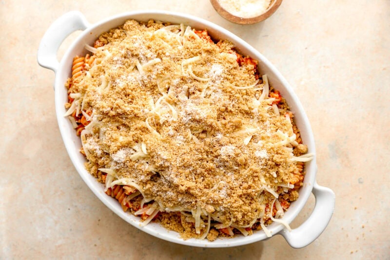 assembled chicken parmesan casserole topped with breadcrumbs in a casserole dish.