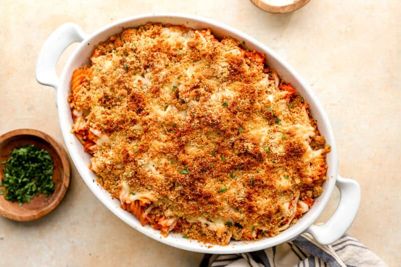 baked chicken parmesan casserole in a baking dish with parsley on the side.