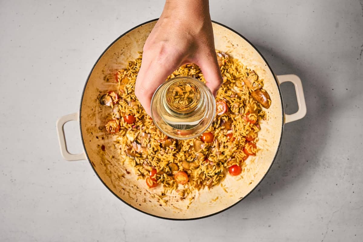 deglazing a pan of orzo and veggies with wine.
