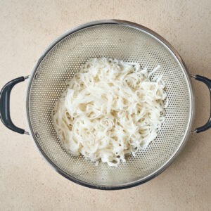 strained cooked rice noodles in a colander.