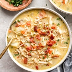 overhead view of a bowl of chicken and potato soup topped with bacon.