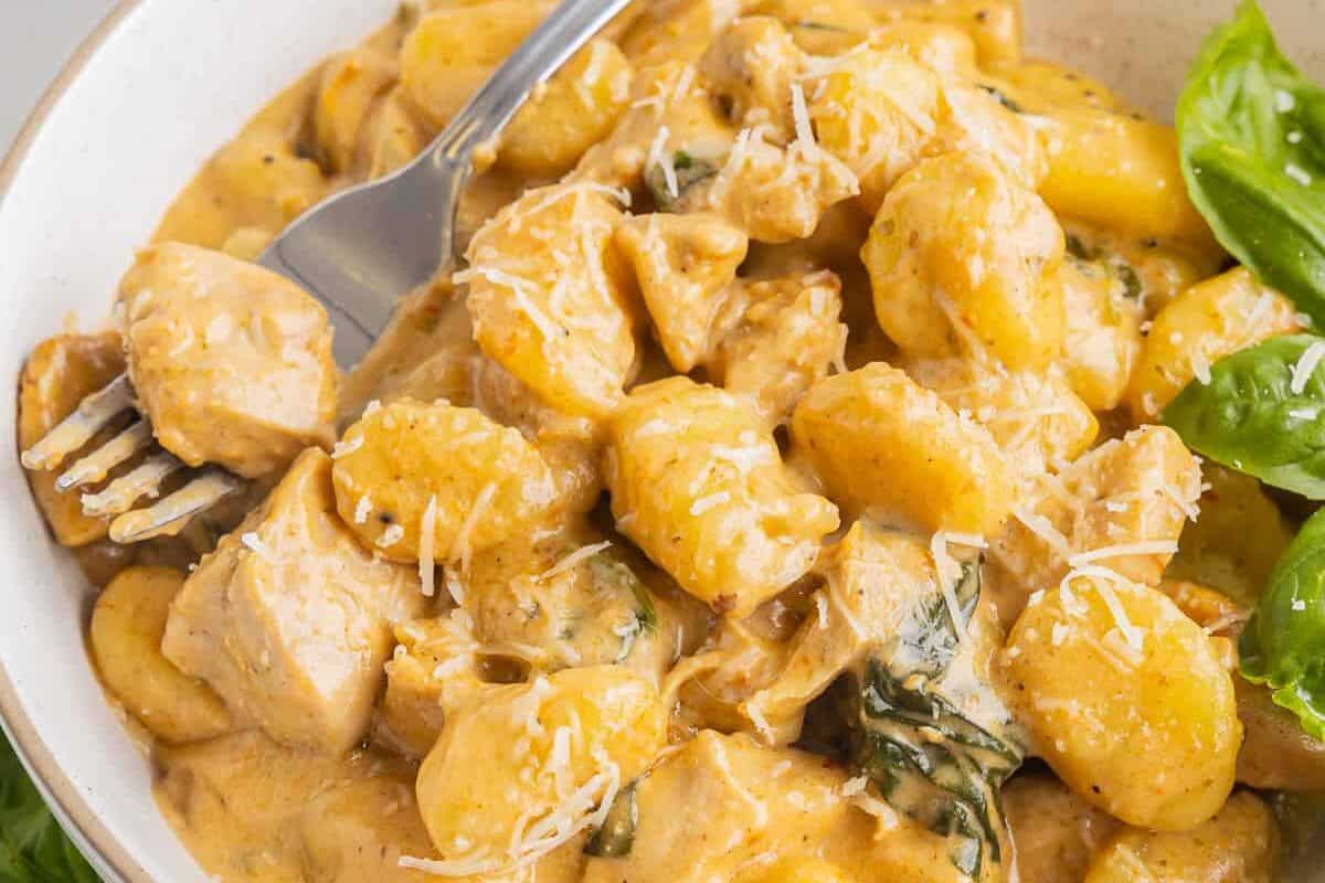 three-quarters view of creamy chicken gnocchi in a bowl with a fork.