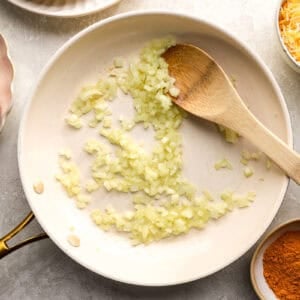 sautéing onion in a frying pan with a wooden spoon.