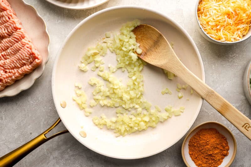 sautéing onion in a frying pan with a wooden spoon.
