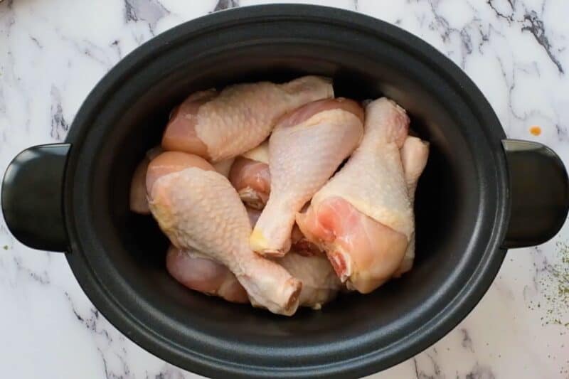 Raw chicken drumsticks in a Crock Pot.