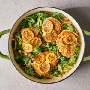 chicken and lemon slices added to broccoli and white beans in a skillet.