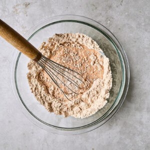 whisked seasoned flour in a glass bowl with a whisk.