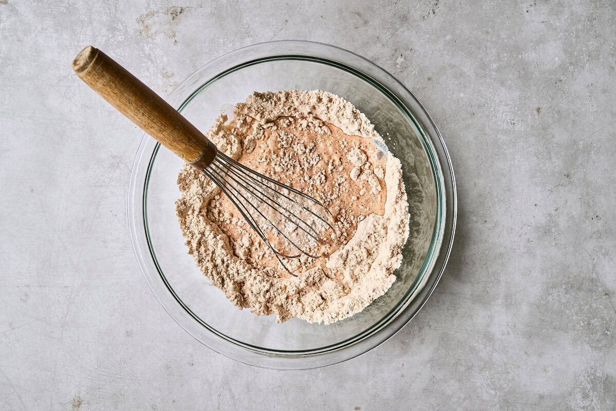 whisked seasoned flour in a glass bowl with a whisk.