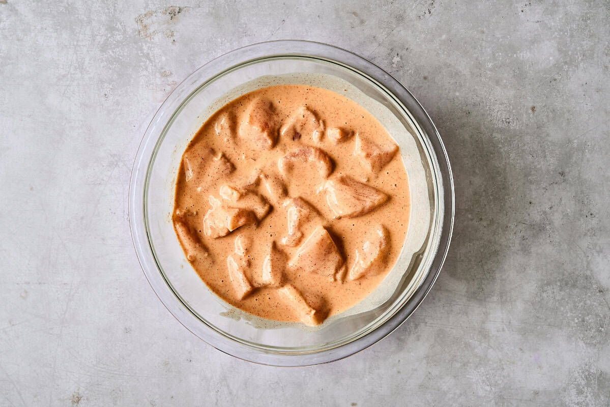 chicken pieces in Sriracha batter in a glass bowl.