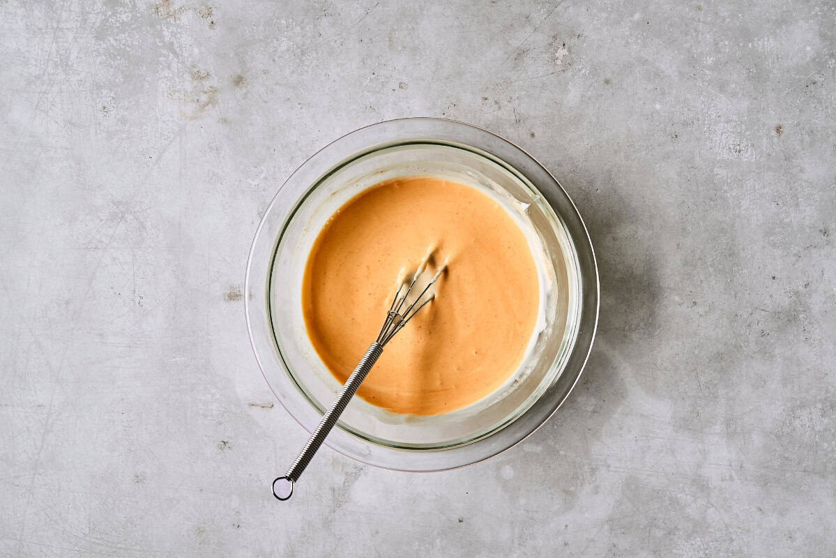 bang bang sauce in a glass bowl with a whisk.
